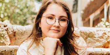A woman with a confident, thoughtful expression wearing glasses; a visual representation of the keen perceptiveness and analytical strengths developed after a hyper-critical upbringing.