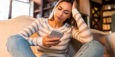 woman who overuses ai and chatgpt feeling dumber looking at phone