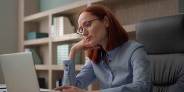 serious female employee working on laptop