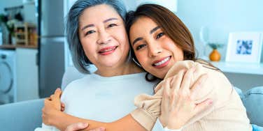 parent hugging grown daughter smiling about their close relationship