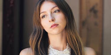 A close-up portrait of a woman with a somber, pensive gaze; illustrating the silent resignation and quiet unhappiness behind the everyday phrases used in failing relationships.