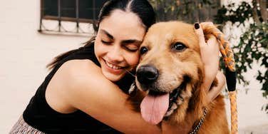 A woman hugging her dog with genuine affection in a natural setting; illustrating the psychological theory that one's relationship with a pet is a primary indicator of their true character and emotional maturity.