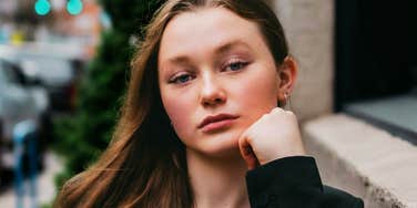 A woman looking at the camera with a calm and strong expression while resting her chin on her hand; illustrating the quick habits of emotional regulation and composure used to navigate high-stress situations.