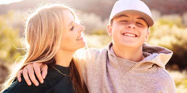 A mother smiling with her teenage son in a candid outdoor shot, representing the fine line between supportive parenting and the emotionally overbearing traits that follow children into adulthood.