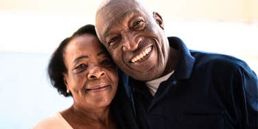 A happy senior couple smiling at home, representing the long-term success of partners who master rare communication skills during heated arguments.