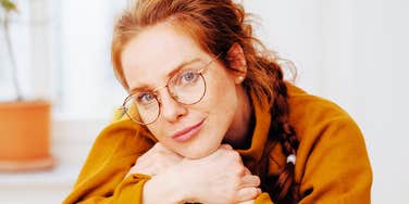 A thoughtful young woman sitting calmly in a chair, embodying the rare "quiet power" traits that allow certain people to manifest success without overworking.