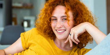 joyful and authentic young woman sitting at home smiling