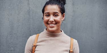 Woman who smiles with a truly beautiful soul by a grey wall