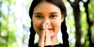 young gen z woman with prayer hands tapping into spirituality