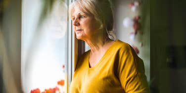 woman over 60 having sad realizations about downsizing looking out the window
