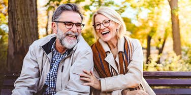 Couple preparing for retirement and laughing together on a park bench