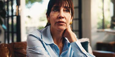 A thoughtful mature adult sitting calmly on a sofa; illustrating the simple habit of reflection that people with exceptional inner strength use when life feels heavy.