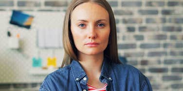 A woman in a casual shirt happily tending to a Christmas tree; illustrating the psychological connection between extended holiday celebrations and personal happiness.