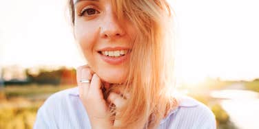 A serene woman in a field of wheat ears at golden hour; a visual of the sensory grounding habits and rare resilience traits that help maintain happiness in difficult seasons.