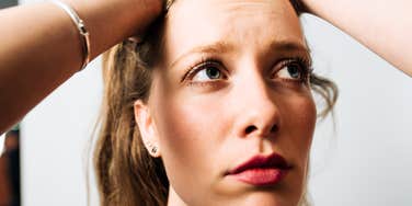 A young woman looking up in deep thought and frustration; a visual representation of analysis paralysis and the mental strain of making a high-stakes decision.