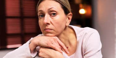 A woman looking lonely on a sofa at home, capturing the 'subtle signs' of midlife stagnation and the beginning of identity consolidation.