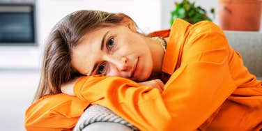 A pensive woman reclining on a sofa in a living room; illustrating the internal shift and the subtle signs that occur when you have naturally moved on from a previous connection.
