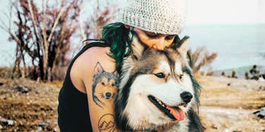A woman hugging her dog with her eyes closed; a visual representation of the deep emotional support pets provide and the therapeutic reasons why their loss impacts humans so deeply.