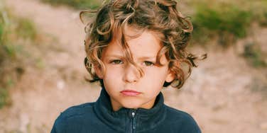 A young boy appearing stoic and pouting, illustrating 'affective blunting' and the psychological barriers to expressing gratitude in childhood.