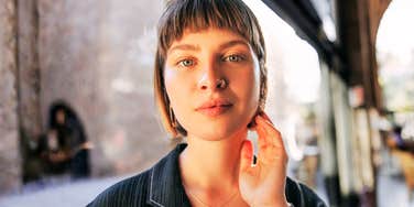 A woman resting her hand on her face with a composed and cheerful look; a visual of the emotional self-regulation habits used by people who remain calm while others are stressed.