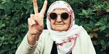 A stylish mature woman gesturing a peace sign with a beaming smile; illustrating the vibrant spirit and fashionable confidence that women in their sixties swear by to embrace their age.