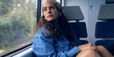 woman sitting on train seat looking out window