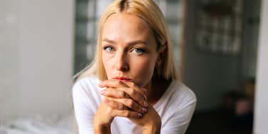 A close-up portrait of a blonde woman with a pensive and sad expression, capturing the silent emotional burden and 'painful secrets' many wives feel unable to share with their husbands.