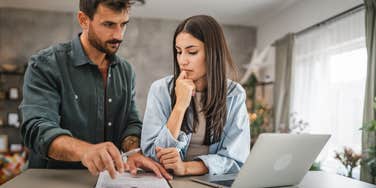 couple at home together signing paper in clipboard