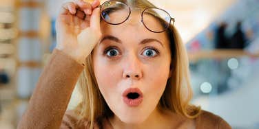 woman lifting glasses getting excited about odd things