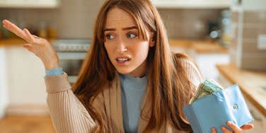 frugal american woman holding wallet looking concerned and annoyed