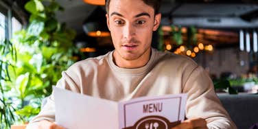 man looking at restaurant menu not knowing how to order