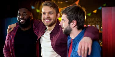 guy friends hugging celebrating bachelor party in bar,
