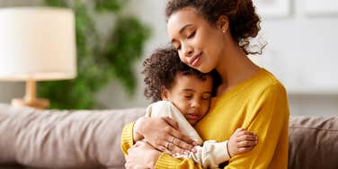 boy mom cuddling with toddler on couch at home