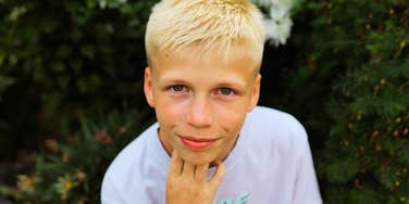 A blonde teenage boy looking directly at the camera with a kind, contemplative expression; illustrating the foundational life lessons and 'soft skills' that shape boys into reliable and loving men.