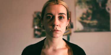 A portrait of a woman indoors with a deeply thoughtful expression; illustrating the quiet strength and the hidden 'disturbing symptoms' that individuals navigate during recovery from toxic relationships.