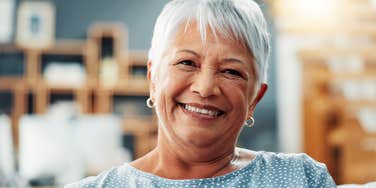 smiling elderly woman sitting on couch at home