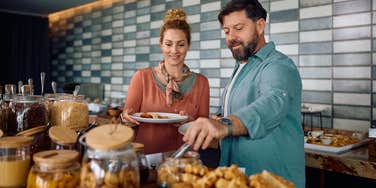 hotel guests putting breakfast on plates during buffet
