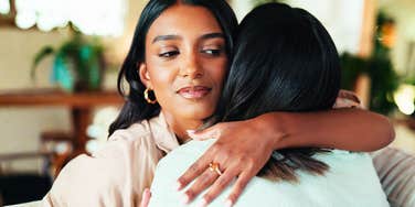 A close-up of an embrace between two people where one person's expression suggests deceit and jealousy; illustrating the 'polite' but secretly manipulative tactics used in toxic relationships.