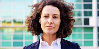 A professional woman in her 50s staring at the camera; illustrating the demographic of Gen X professionals who have pivoted to 'perpetual employment' as a primary retirement strategy.