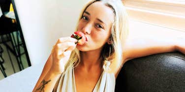 A young woman holding a strawberry, capturing the aesthetic of the 'Strawberry Generation' moniker; illustrating the generational divide between traditional 'grit' and the modern Gen Z focus on emotional boundaries and mental well-being.
