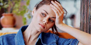 A woman looking overwhelmed and anxious at home; illustrating the emotional burden experienced by adult children when questioning why their Boomer or Gen X parents appear to resent them.
