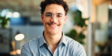 Genuinely confident man in glasses smiles at the camera 