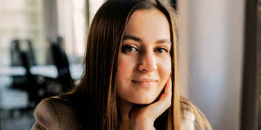 A professional woman looking at the camera with a steady, self-assured gaze in an office setting; illustrating the confidence and analytical focus characteristic of high-IQ individuals who achieve exceptional life goals.