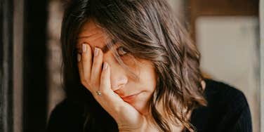 A close-up of a woman looking somber and overwhelmed with her hand to her head; illustrating the 'honest reasons' why verbal apologies often fall short without genuine emotional resonance or behavioral change.