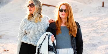 One woman leaning on another's shoulder in a show of trust, while the supporting friend looks visibly drained; illustrating the 'exhausting' reality and eventual betrayal that can occur in high-stakes personal relationships.