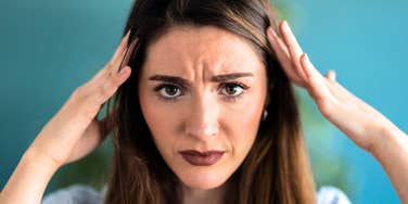 high iq woman holding her head in pain after boring conversation