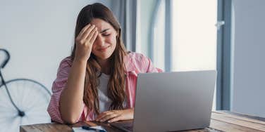 frustrated woman sitting in front of open laptop at desk