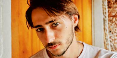 A man looking skeptical and pensive; illustrating the 'emotional vigilance' and internal questioning that occurs when a man feels a lack of transparency or consistency in his relationship.