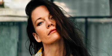 A portrait of a fashionable woman in a yellow floral top against a Berlin backdrop; illustrating the 'covert' nature of toxic behavior and the common traits that high-conflict personalities use to manipulate their environment.