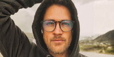 A handsome man with light facial hair and glasses looking happy and thoughtful outdoors; illustrating the 'initial attraction' phase that can quickly fade due to the specific negative traits identified by relationship experts.